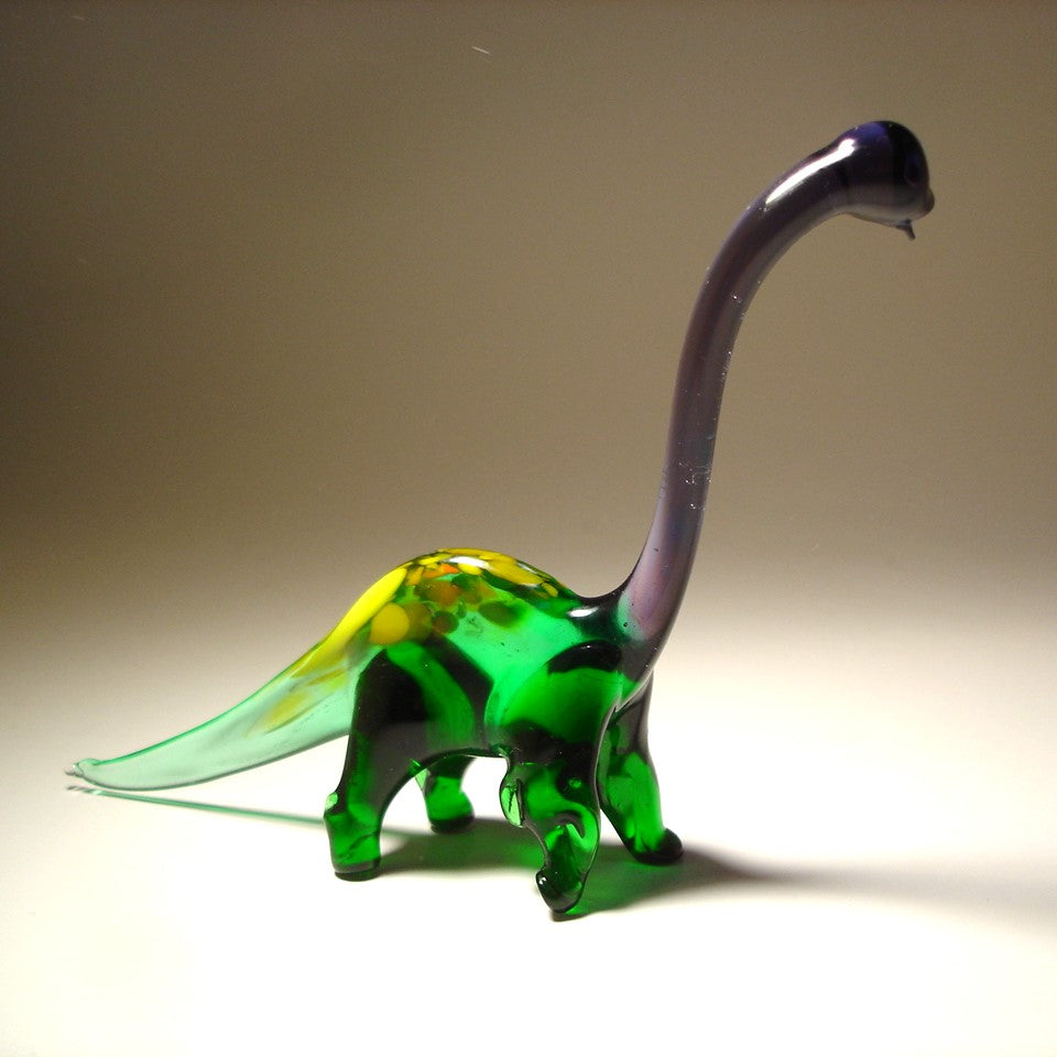 Glass dinosaur figure with a green body and purple neck on a beige background.