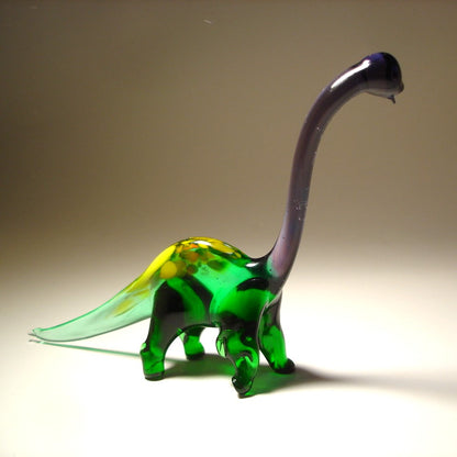 Glass dinosaur figure with a green body and purple neck on a beige background.