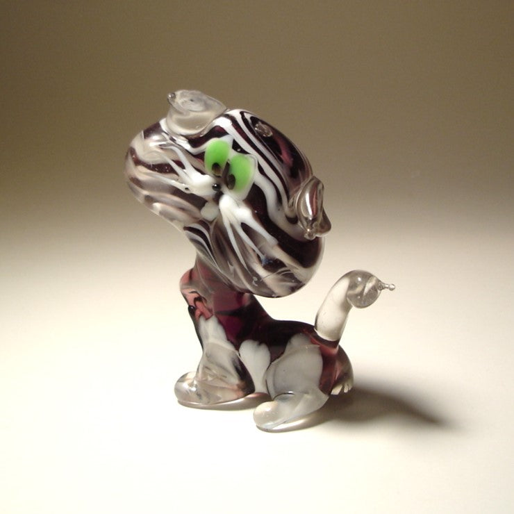 A side view of a glass striped cat figurine, emphasizing its elegant posture and perked clear glass ears.