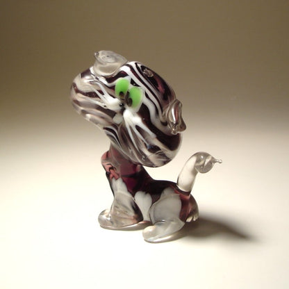 A side view of a glass striped cat figurine, emphasizing its elegant posture and perked clear glass ears.