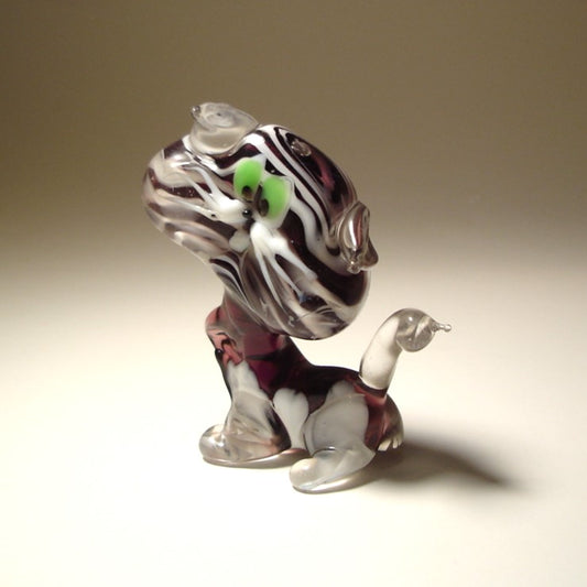 A side view of a glass striped cat figurine, emphasizing its elegant posture and perked clear glass ears.
