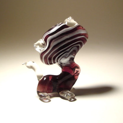 A back view of a glass striped cat figurine, highlighting the unique striped design along its back and clear glass tail.