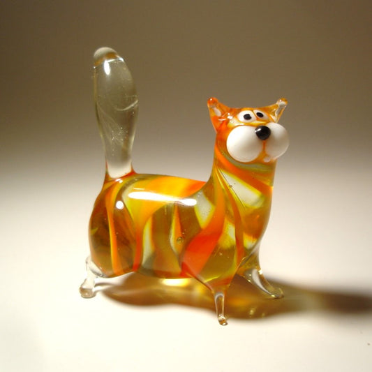A handmade orange glass chubby cat figurine, standing with its clear glass tail pointed straight up. 