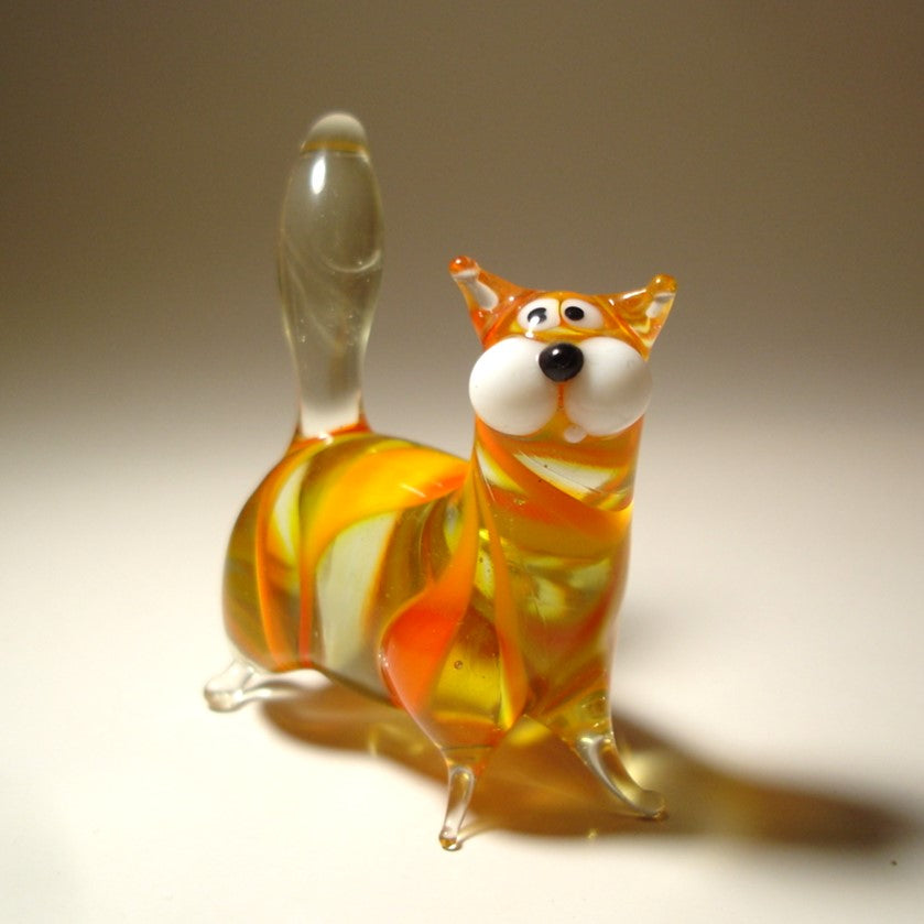 A side view of the glass chubby cat figurine with white face, highlighting its plump body and upright clear glass tail. 