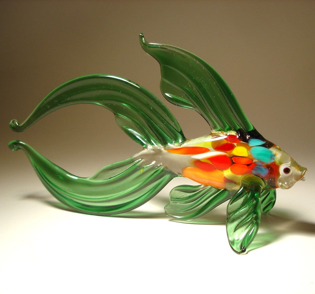 A side profile of the handmade green glass Betta fish figurine, highlighting its long, graceful fins that fan out elegantly behind the body. 