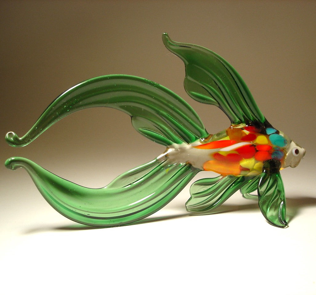 Glass fish sculpture with green body and multicolored belly on a beige background