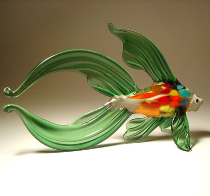 Glass fish sculpture with green body and multicolored belly on a beige background