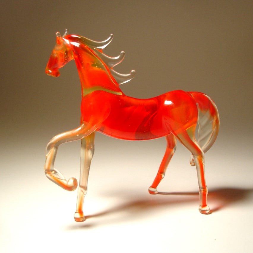 A back view of a red glass horse figurine, featuring its raised left foot, arched neck, and a flowing mane.