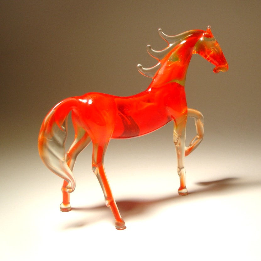 Glass horse sculpture with a bright red hue on a gradient background