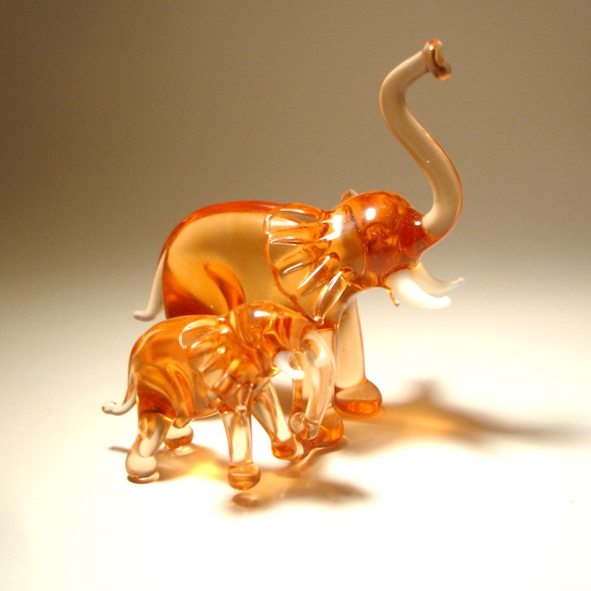 A close-up of the glass elephant and baby duo showcases their detailed trunks lifted up.