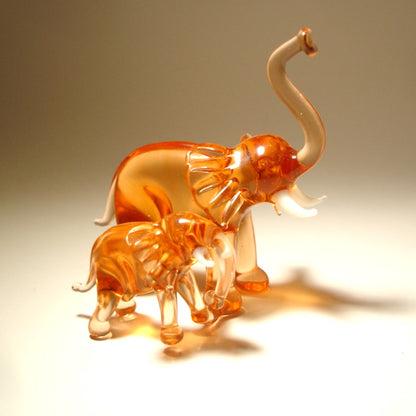 A close-up of the glass elephant and baby duo showcases their detailed trunks lifted up.