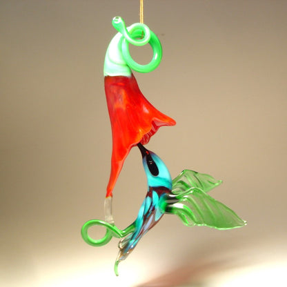 Glass Red flower and a yellow and Green hummingbird suspended from it,  as  if drinking nectar