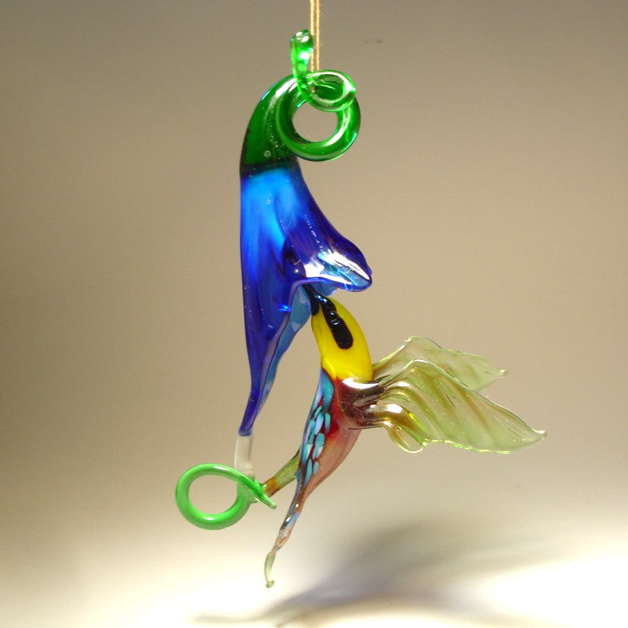 Glass red and green hummingbird figurine hovering next to a vibrant blue flower ornament