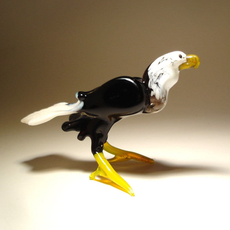Glass sculpture of an eagle with a white head and black body on a beige background