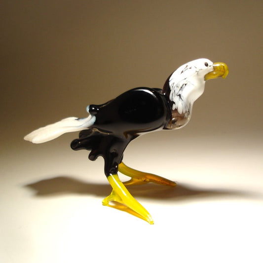 Glass sculpture of an eagle with a white head and black body on a beige background