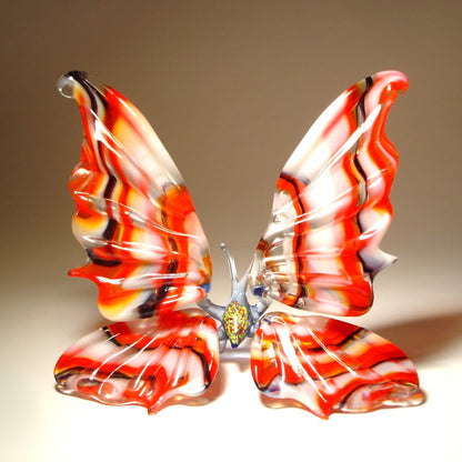 A front view of a handcrafted glass butterfly figurine, showcasing its vibrant colors and intricate striped wing pattern.