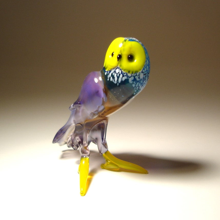 Front view of a standing glass owl figurine with expressive yellow face and black eyes.