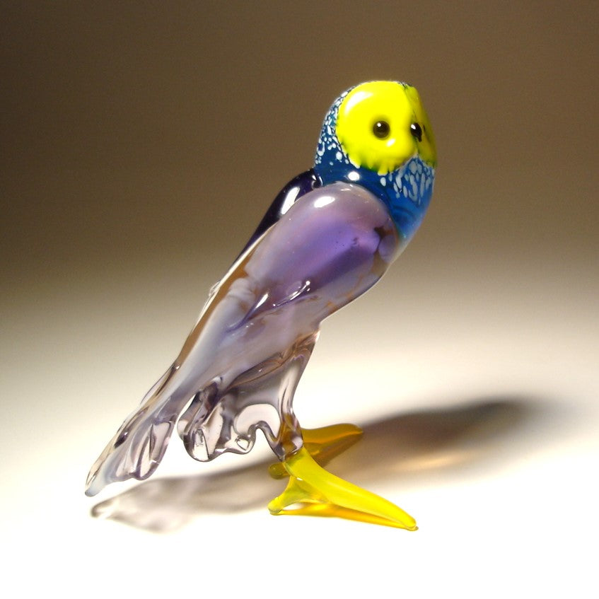 Side view of the lilac and blue glass owl, showcasing its charming expression and the vibrant contrast between the lilac body and yellow face. 