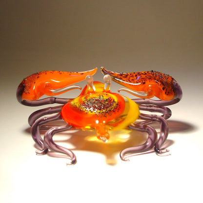 Front view of a glass crab figurine with vibrant red claws, showcasing its detailed colorful shell and legs.