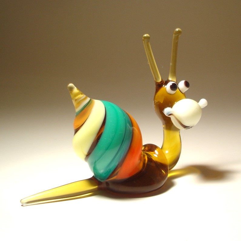 Side view of the Glass Happy Snail Figurine, displaying its colorful spiral shell as it appears to crawl, with its cheerful expression.
