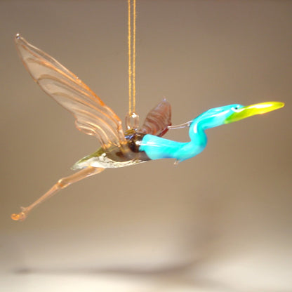 Side view of the Glass Heron in Flight Hanging Figurine, highlighting the bird's graceful posture and elongated neck mid-flight.