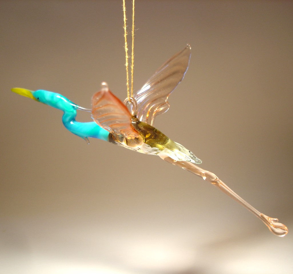 Glass figurine of a heron bird with a blue neck on a beige background