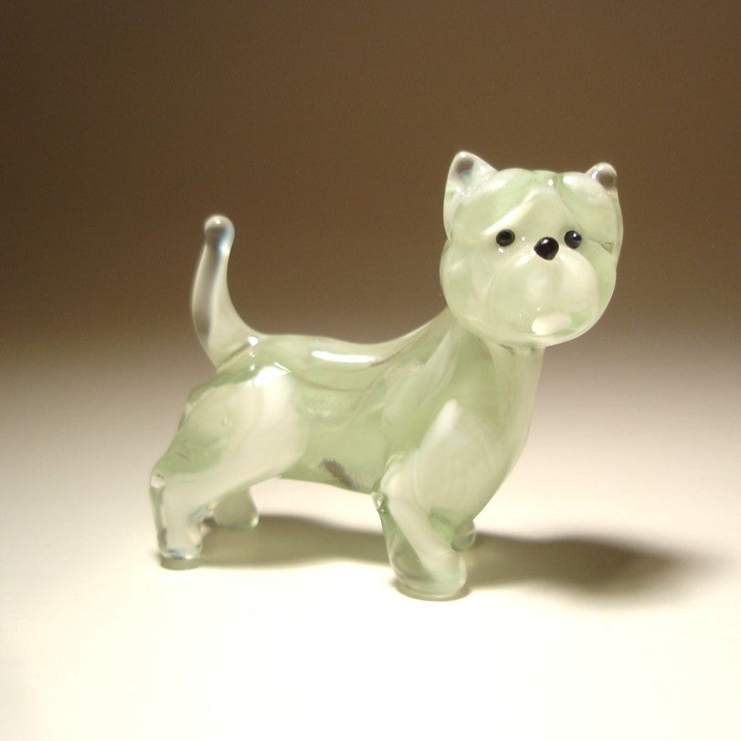 A close-up view of the glass West Highland Terrier figurine highlights its expressive face, with black eyes and nose.