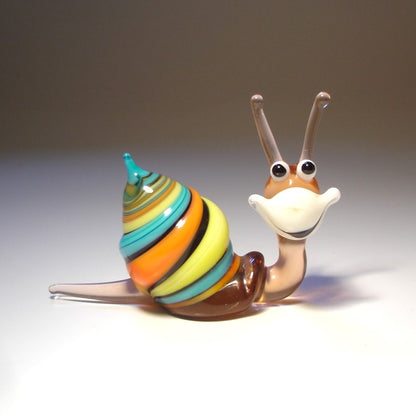 A close-up of a comical Glass Happy Snail Figurine smiling.