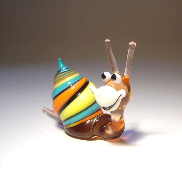 Side view of the Glass Happy Snail Figurine, displaying its colorful spiral shell as it appears to crawl, with its cheerful expression.