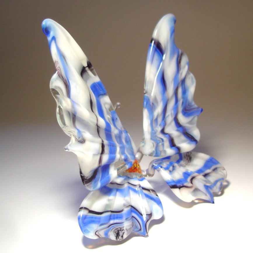 Another side view of a white and blue striped glass butterfly figurine positioned on a surface.