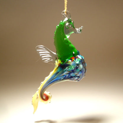 Another side view of the glass hanging seahorse ornament, showcasing its red and white colors and curled tail.