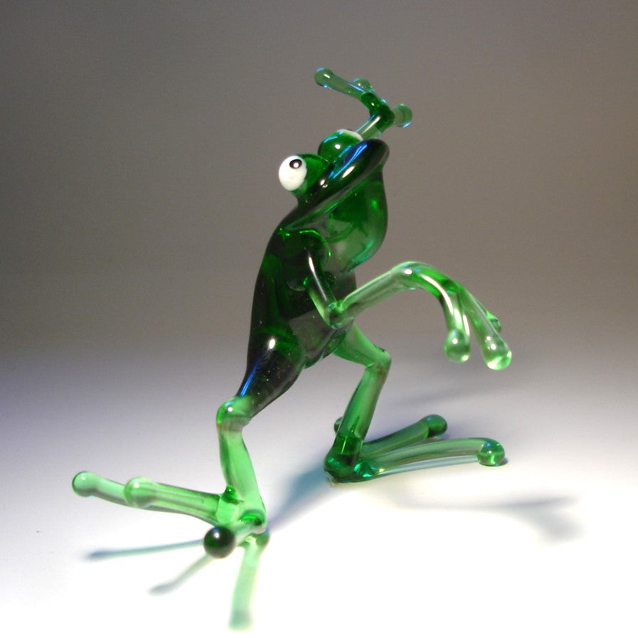 Handmade glass frog figurine in a dancing pose, with one leg slightly lifted and arms gracefully extended.