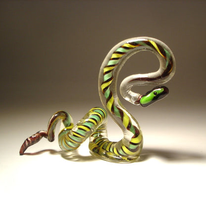 A side view of a glass snake figurine, with its head raised and ready to strike.