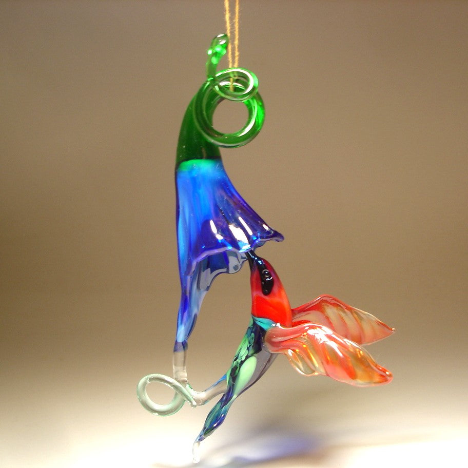 Glass ornament featuring a hummingbird drinking nectar from a blue trumpet flower.
