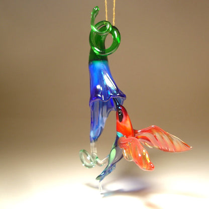 Glass red and green hummingbird figurine hovering next to a vibrant blue flower ornament