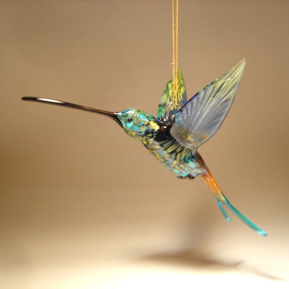 Left side view of the suspended in air hummingbird showcasing a transparent blue wings.
