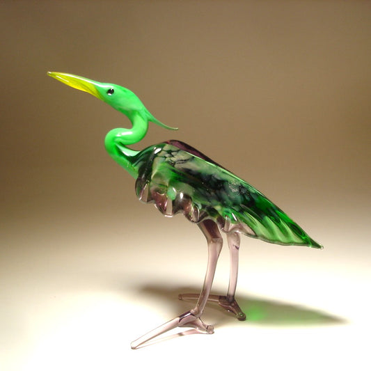 A side view of the glass heron figurine highlighting its green-purple back and intricate feathers on the side of its body.