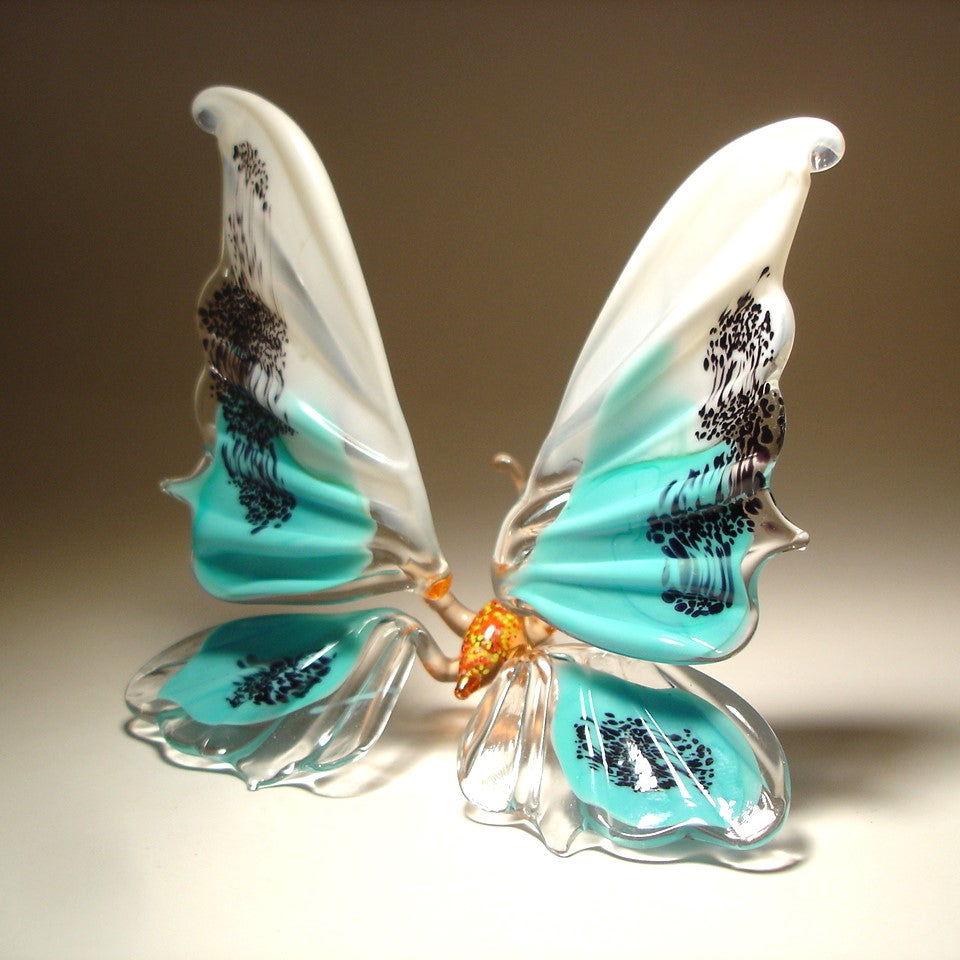 A side view of the white and blue glass butterfly figurine, showcasing its graceful shape and the artistic design of its wings.