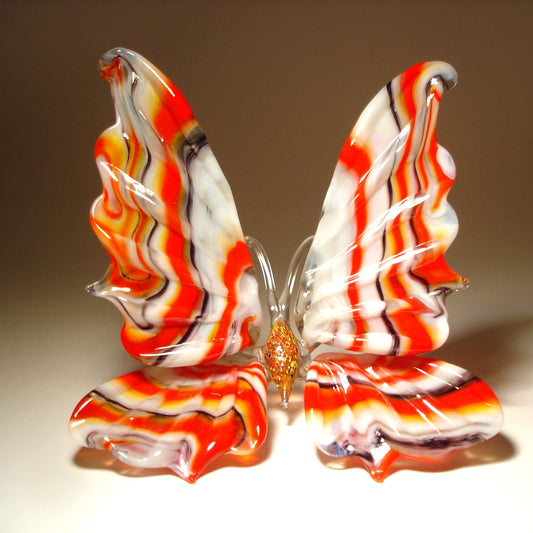 A front view of a handcrafted glass butterfly figurine, showcasing its vibrant colors and intricate striped wing pattern.