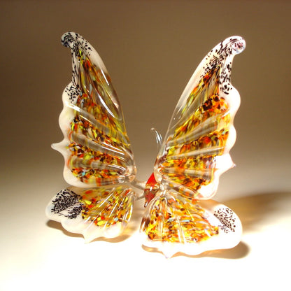 A side angle of the white glass butterfly figurine, emphasizing the elegant curves of its extended outward wings.