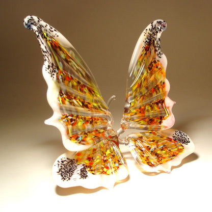 Aside view of a handmade butterfly sitting with wings trimmed in white and multicolored  specs.