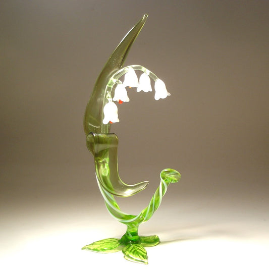 A delicate glass Lily of the Valley flower figurine, showcasing its slender stem, green leaves  and white bell-shaped flowers.