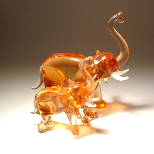 Two glass elephants, one larger and one smaller with raised trunks