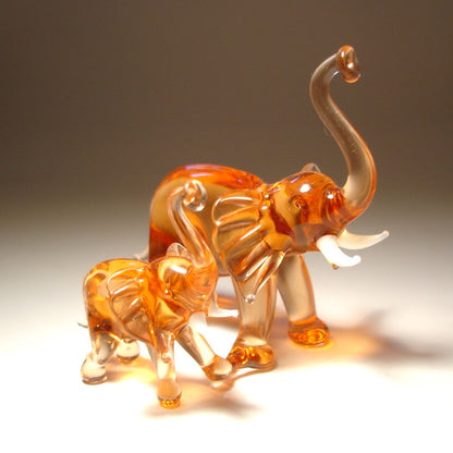 side view of two glass elephant figures on a plain background