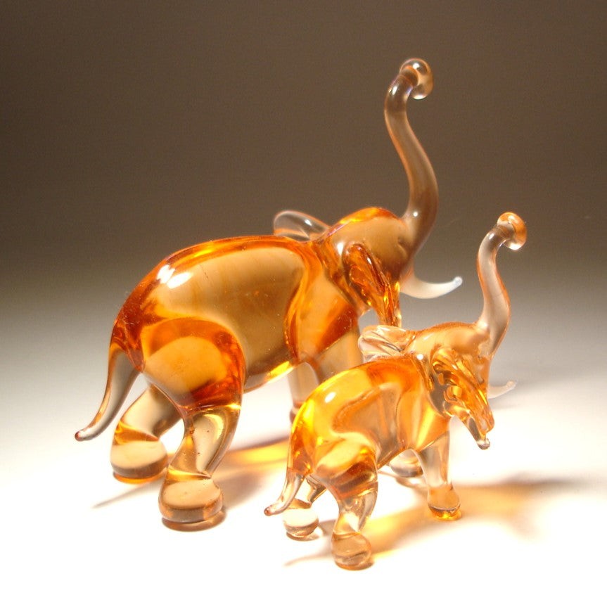 A handcrafted glass elephant figurine with a baby elephant beside it in beige color.