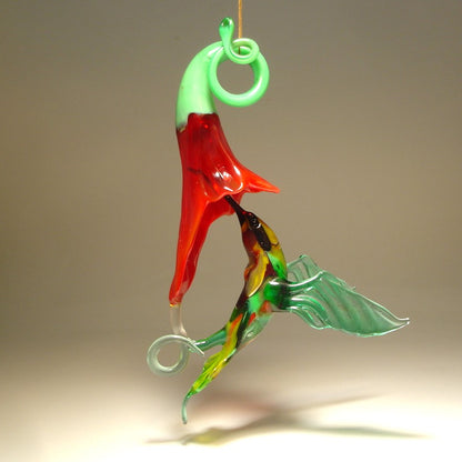 Glass Red flower and a yellow and Green hummingbird suspended from it,  as  if drinking nectar