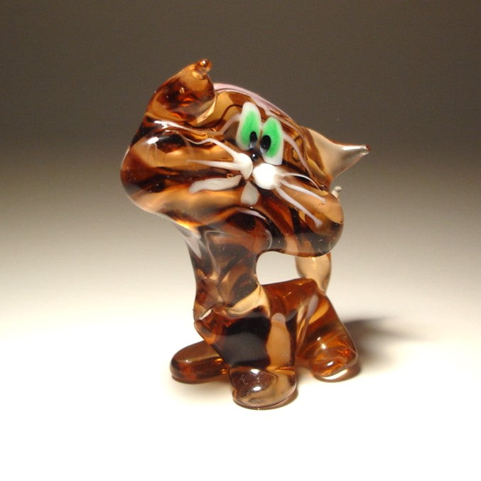 A side view of a glass striped cat figurine, emphasizing its elegant posture and perked clear glass ears.