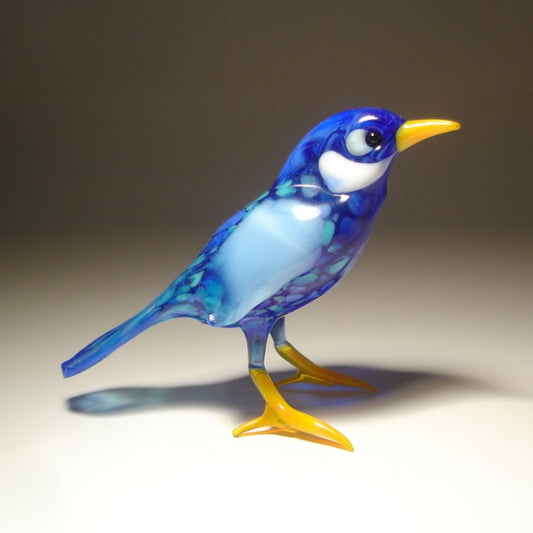 Side view of a glass bluebird figurine, highlighting the detailed wings in lighter blue and craftsmanship of its head and white cheeks.