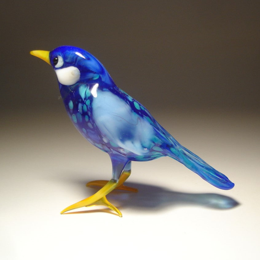 Front view of the glass bluebird figurine, focusing on its intricate beak, feathers, and glossy blue color.