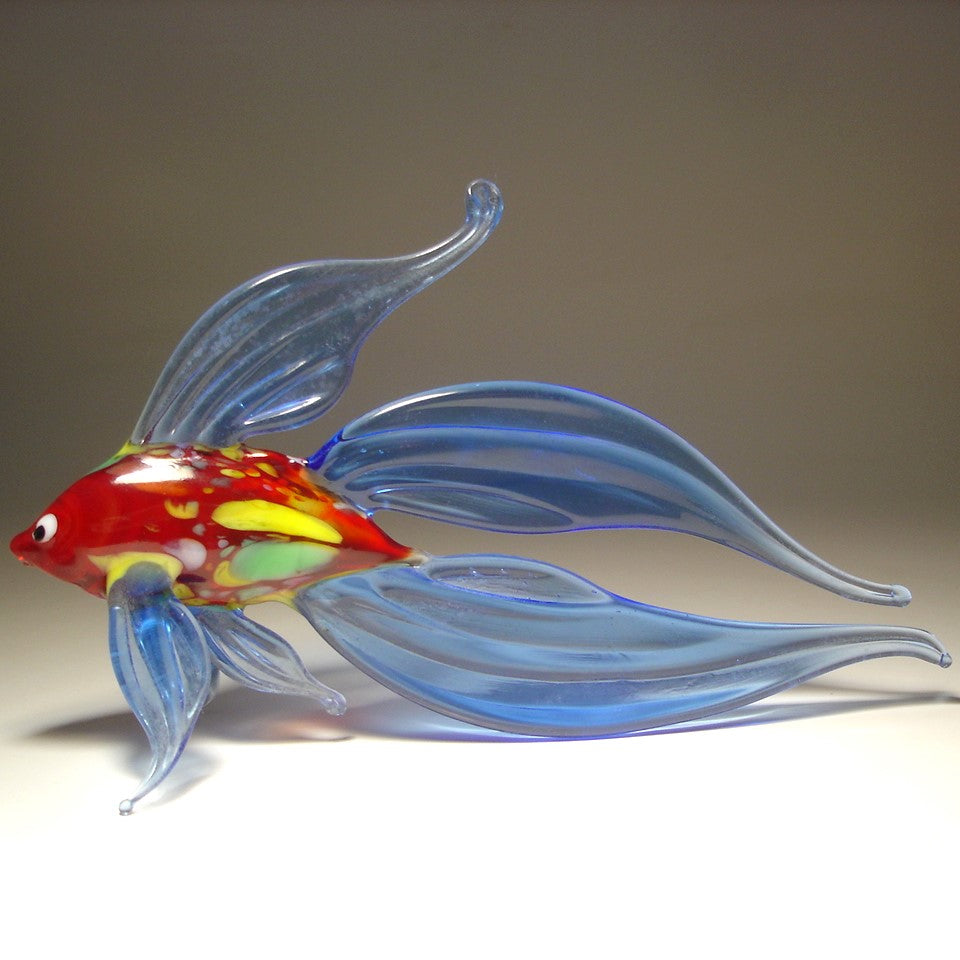 A hand-blown glass fish sculpture with translucent blue wings and a red, yellow, and green glass body.